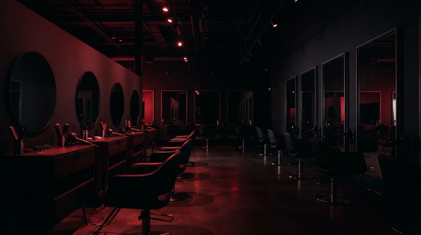 Interior de un salón de belleza vacío de noche con luz roja tenue sobre los espejos
